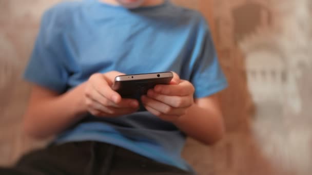 Niño irreconocible de siete años navegando por Internet en su teléfono móvil . — Vídeos de Stock