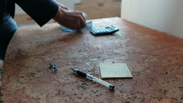 Muž se počítá peníze, položil je na stůl s kalkulačkou. Closeup ruce. — Stock video