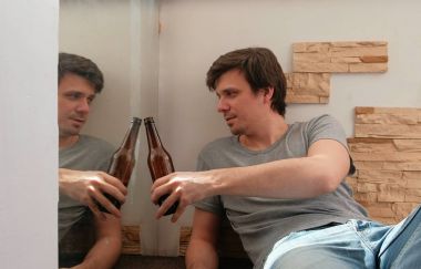 Erkek lisans ile onun yansıması aynaya bira ve kodes şişe içme.