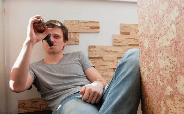 Male bachelor drinking beer laying on the balcony.