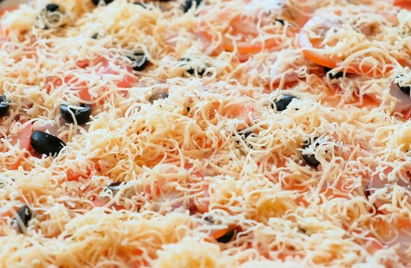 Кук готовит пиццу. Пицца крупным планом с тертым сыром, соусом, оливками, помидорами и беконом . — стоковое фото
