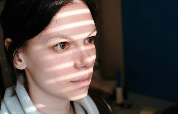 Close-up de um rosto de mulher morena com listras de luz da janela em seu rosto . — Fotografia de Stock