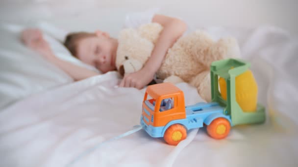 Hét-év-régi fiú alszik a medve játékok és műanyag autó. A hangsúly a játékautó. — Stock videók