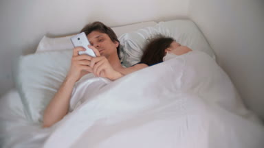 Karısı uzakta uyurken koca içinde hareket eden telefon, bir şey izliyor.