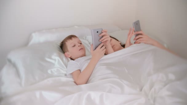 Maman et fils se réveillent et naviguent sur Internet dans leurs téléphones mobiles, vue de face . — Video