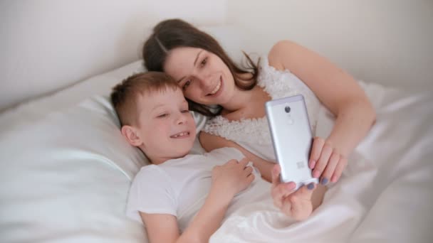 Moeder en zoon nemen selfie op haar mobiele telefoon. Moeder hugs haar zoon. — Stockvideo