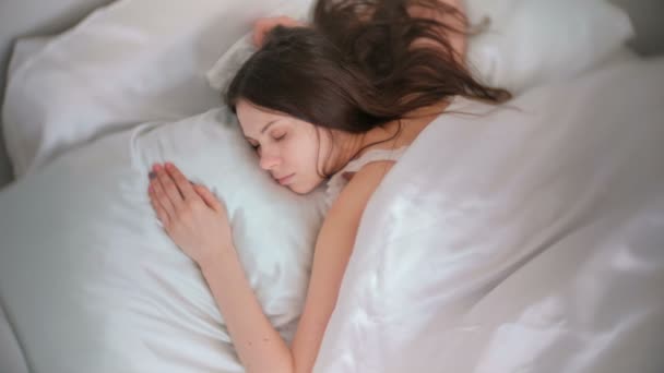 Молода жінка брюнетка спить у ліжку . — стокове відео