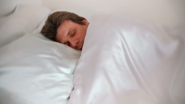 El hombre está durmiendo en la cama solo debajo de la manta. Vista lateral . — Vídeos de Stock