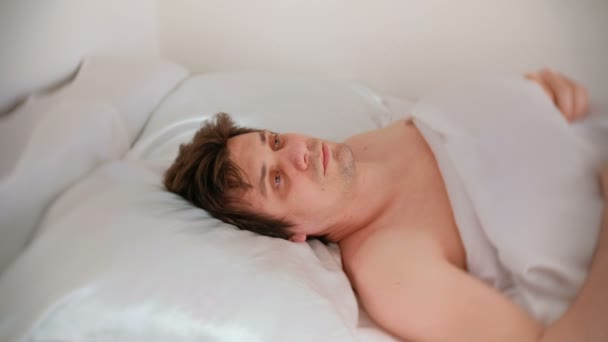 Μελαχροινός όμορφος νεαρός πέφτει κοιμισμένος ξαπλωμένη στο κρεβάτι. — Αρχείο Βίντεο