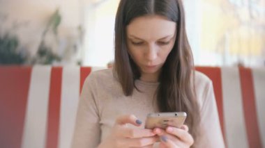 Cep telefonu kafede Internet tarama ve arkadaşları bekleyen genç güzel kadın esmer