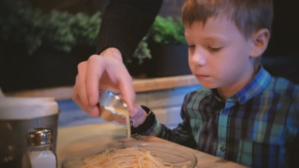 Chłopak wygląda jak tata wlewa spaghetti z olej masło. — Wideo stockowe