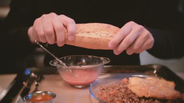 Man eats lunch in a cafe. Breaks the baguette and eats soup. Closeup mans hands. — Stock Video