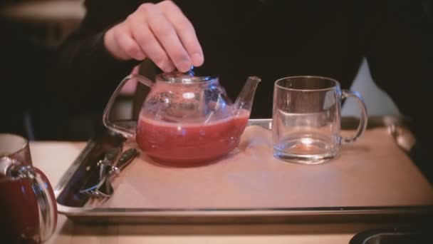 Man giet wat cranberry thee van theepot tot kopje. Close-up mans handen. — Stockvideo