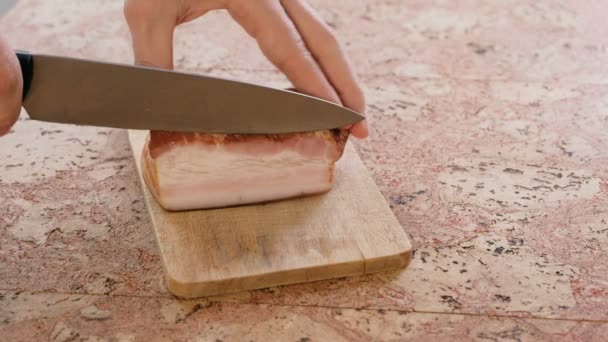 Man skär en pork brisket bacon på skivor på en träskiva. — Stockvideo