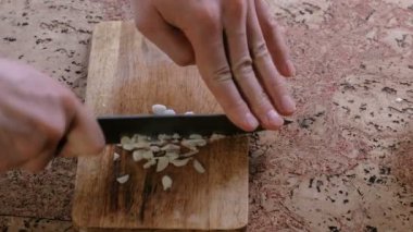 Adam bir ahşap tahta üzerine sarımsak keser. Yakın çekim yakışıklı adamın.