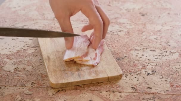 El hombre corta la carne de cerdo por el tocino en los pedazos pequeños sobre la tabla de madera . — Vídeo de stock