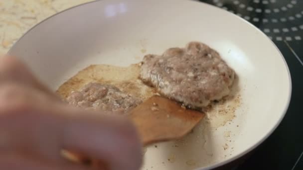Man is op de pan schnitzels voor hamburgers bakken. Close-up van de handen. — Stockvideo