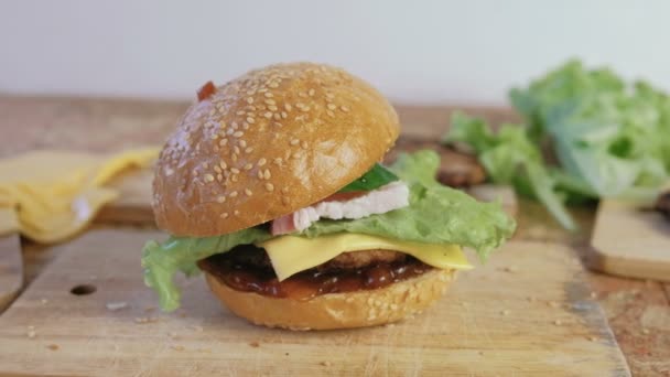 Hausgemachter Burger mit Brötchen, Schnitzeln, Käse, Salat, auf dem Holzbrett. — Stockvideo