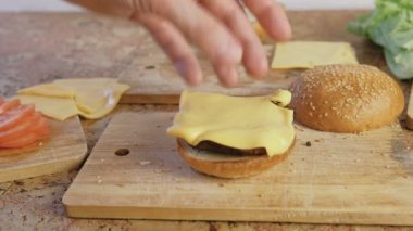 Adam burger buns, domates, salatalık, beşamel sos, peynir, salata, sos, domuz pastırması ile yapar. Yakın çekim yakışıklı,