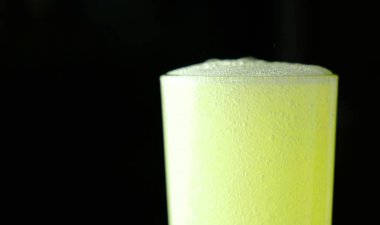 Portre ile sarı gazlı içecek ile dolu cam yarısı siyah bir arka plan üzerinde köpük.