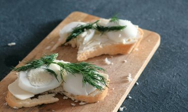 Ekmek, tereyağı, yumurta ve dereotu ahşap tahta siyah arka plan üzerinde closeup sandviç. Bir sandviç yapmak.