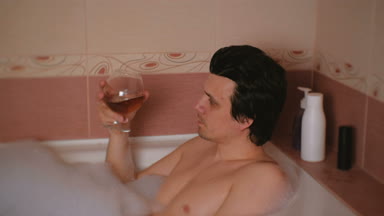 Genç adam bir banyo köpüğü ile alır ve viski içiyor. Dinlenme ve rahatlama işten sonra.