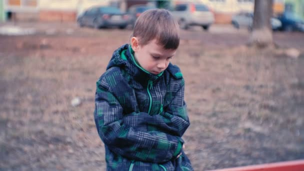 Trieste jongen zittend op een bankje. Jongen is verloren en wachten op ouders. — Stockvideo