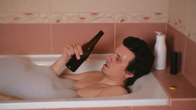 Sarhoş genç adam bir banyo köpüğü ile alır ve içecekler bira.