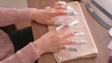 Kaldırma jel Lehçe çivi üzerinden. Tüm parmakları ile folyoyu iki elle. Yakın çekim el.