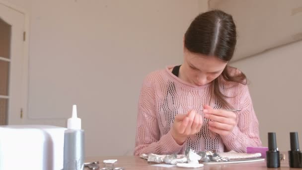 Vrouw ruimt de overblijfselen van schellak uit de nagels met de Opdringer. — Stockvideo