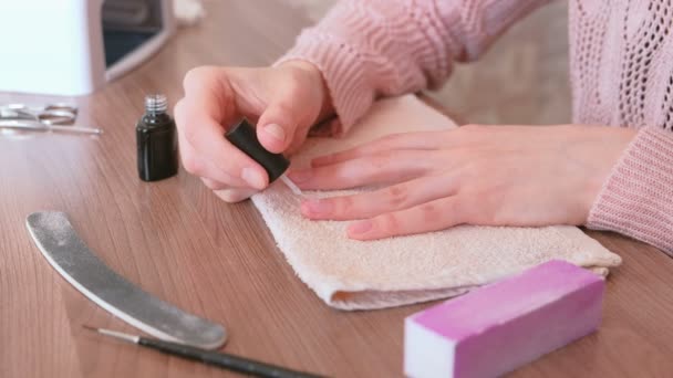 Vrouw zet een grondlaag van schellak op haar nagels. Close-up handen. — Stockvideo