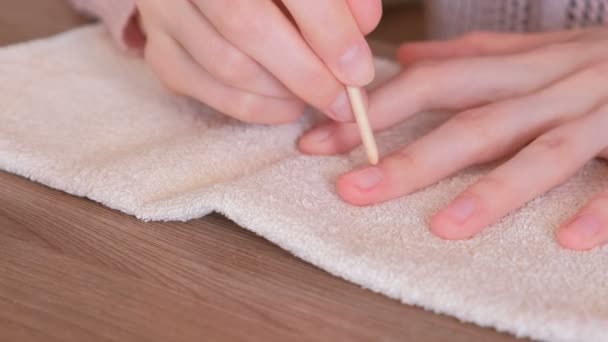 Kvinna rengör överflödigt nagellack med orange träpinne för manikyr. — Stockvideo