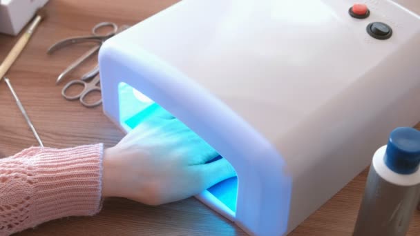 Женщина вытирает ногти Шеллаком в ультрафиолетовой лампе. Крупный план . — стоковое видео