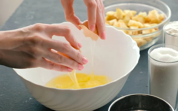 Close-up womans hands break the eggs into white bowl. Cooking apple pie. — Stock Photo, Image