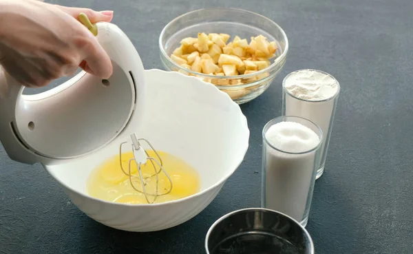 Närbild kvinnans händer med en mixer Vispa ägg med socker i en skål. Matlagning äppelpaj. — Stockfoto