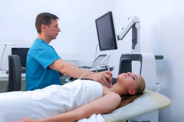 Erkek doktor, ultrason tarayıcısı kullanan ung kadınının tiroid bezi..