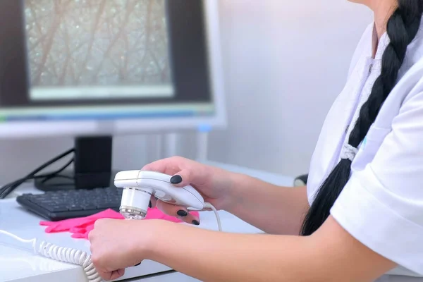 Läkare trichologist exaines kvinnliga patienter hårstrån använder dermatoskop på kliniken. — Stockfoto