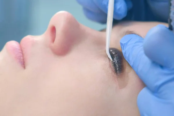 Kozmetikçi kirpikleri iğneyle bigudilere büker, kirpikleri kaldırır..