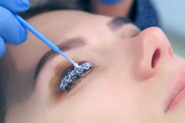 Beautician applying solution for lamination on lashes, lift eyelashes procedure.