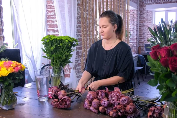 Floristería mujer trabaja hace ramo de peonías de color marrón granate en floristería . — Foto de Stock