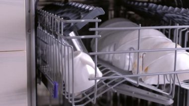 Mutfakta bulaşık makinesinde kirli beyaz tabaklar.