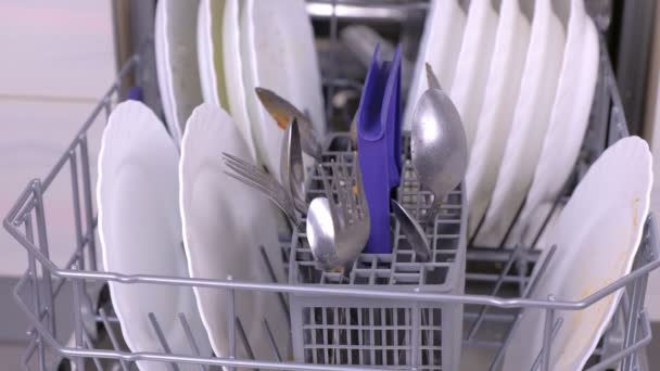 Mans hand is het zetten van een witte vuile plaat en lepel in de vaatwasser en het runnen van het in de keuken. — Stockvideo