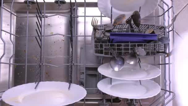 Mans hand is putting a white dirty plates in the dishwasher basket and pushing it inside. — ストック動画