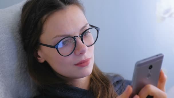 Mujer en gafas está navegando y buscando en las redes sociales en el teléfono inteligente . — Vídeos de Stock