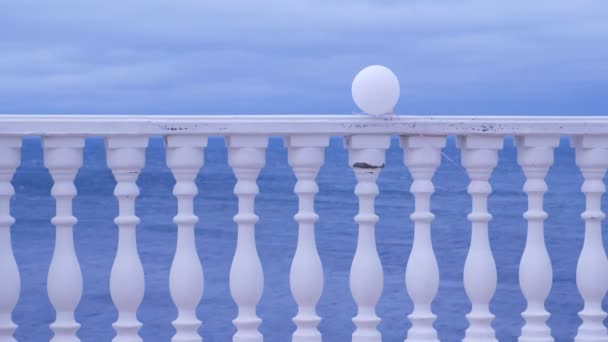 Clôture blanche avec ballon sur le front de mer par une journée nuageuse. Beau paysage marin . — Video