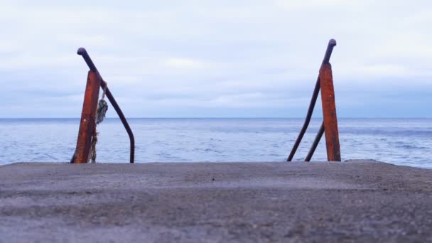 Металлическая ржавая лестница на старом пирсе на морском фоне . — стоковое видео