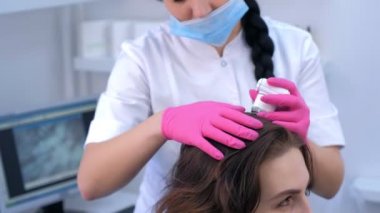 Doktor trichologist klinikte trikop kullanan kadın hasta kıllarını inceliyor..