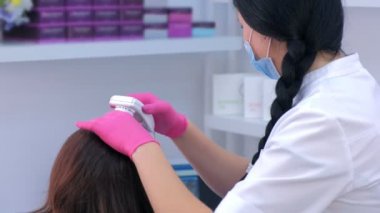 Trikoloğum klinikte bilgisayar trikoskopisi kullanarak kadın hasta kıllarını inceliyor..