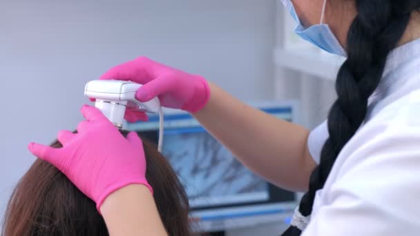 Lékař tricholog vyšetřuje ženy vlasy pomocí trikhoskopu na klinice. — Stock video