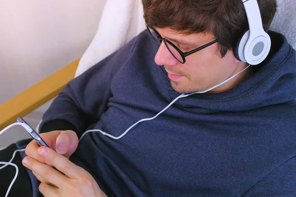 Man in glasses and headphones playing a game in smartphone, side view. Gamer relax. — ストック写真